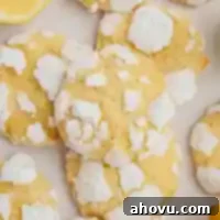 Several perfectly baked lemon crinkle cookies with a pristine powdered sugar coating, artfully arranged on a piece of parchment paper.