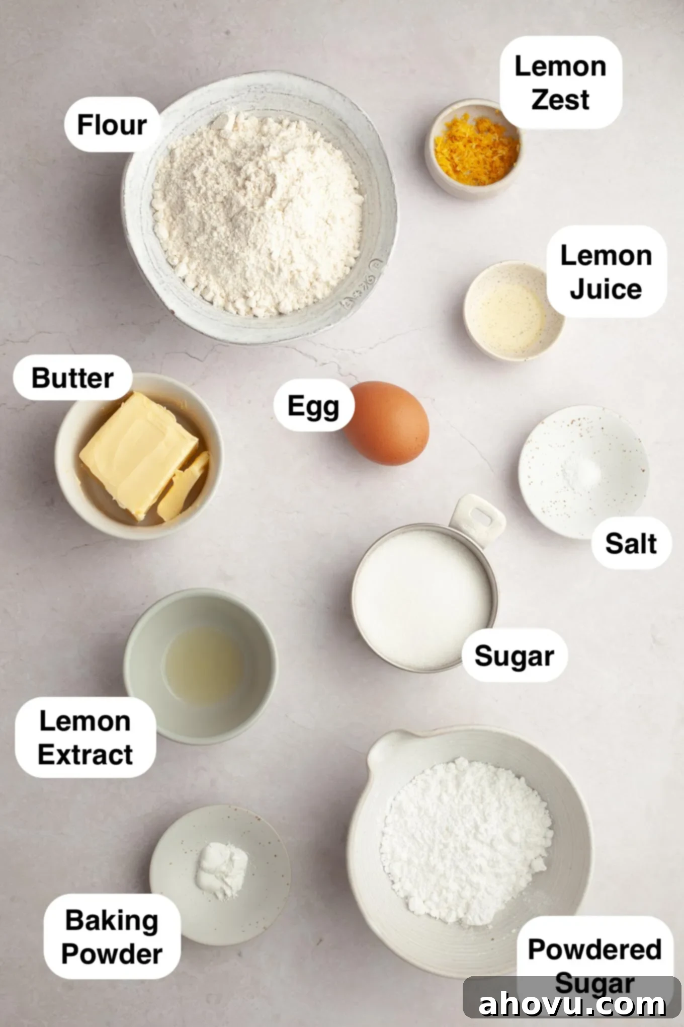 An overhead view of fresh lemons, butter, sugar, flour, and other ingredients laid out for making lemon crinkle cookies.
