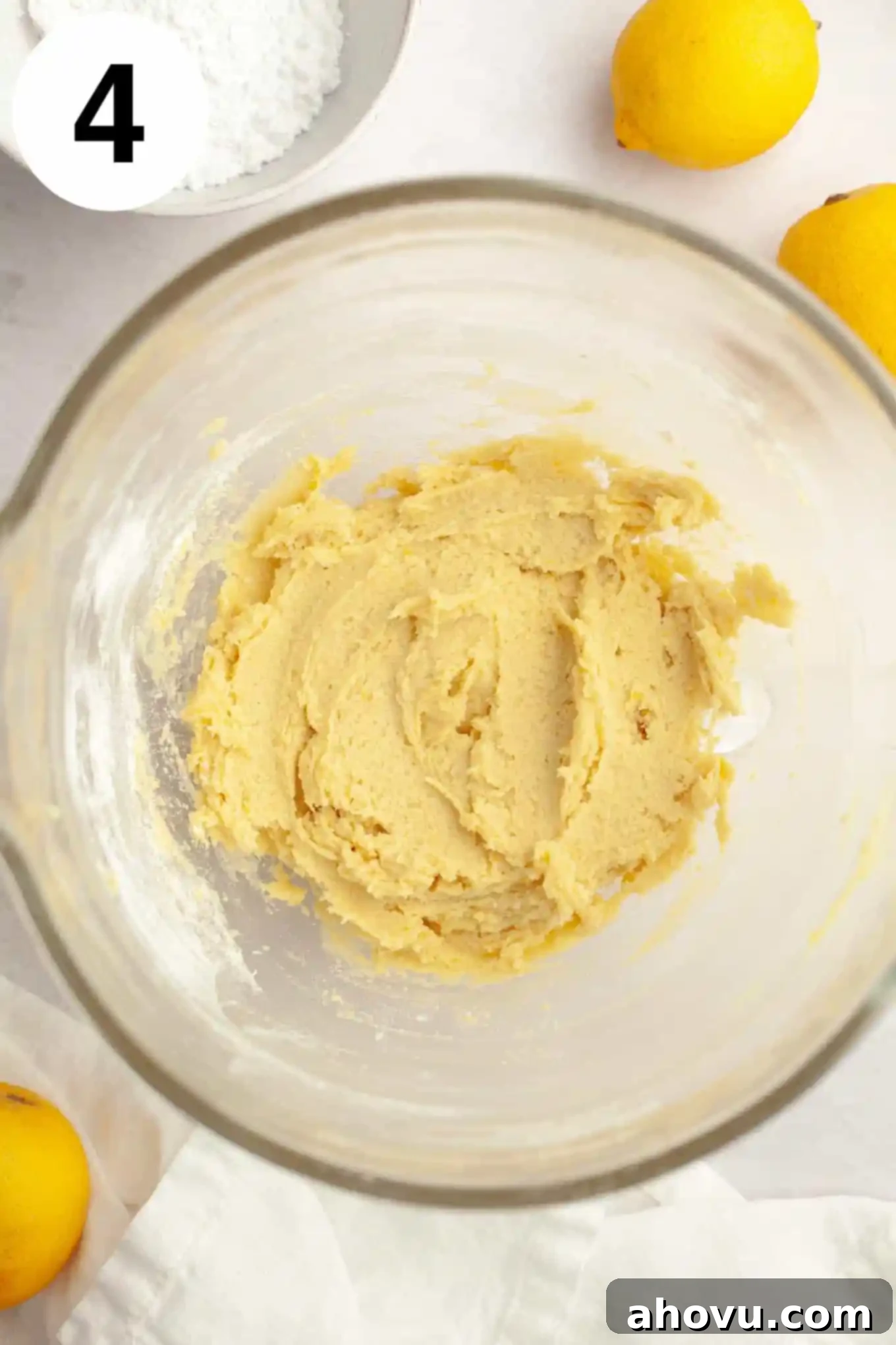 An overhead view of freshly mixed lemon cookie dough in a glass mixing bowl, ready for chilling.