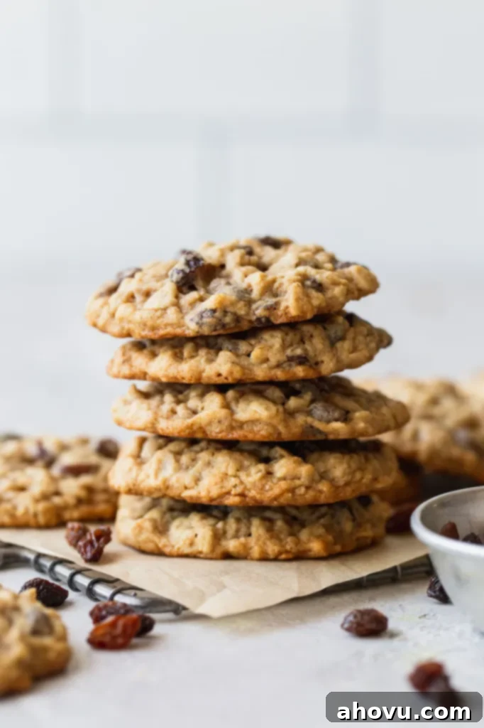 A stack of golden-brown oatmeal raisin cookies, perfectly baked, resting on a cooling rack lined with parchment paper, highlighting their soft and chewy texture.