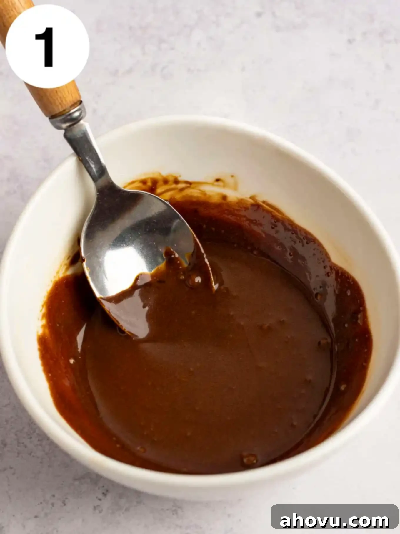 A small white bowl containing instant coffee granules and a small amount of heavy cream, mixed together.