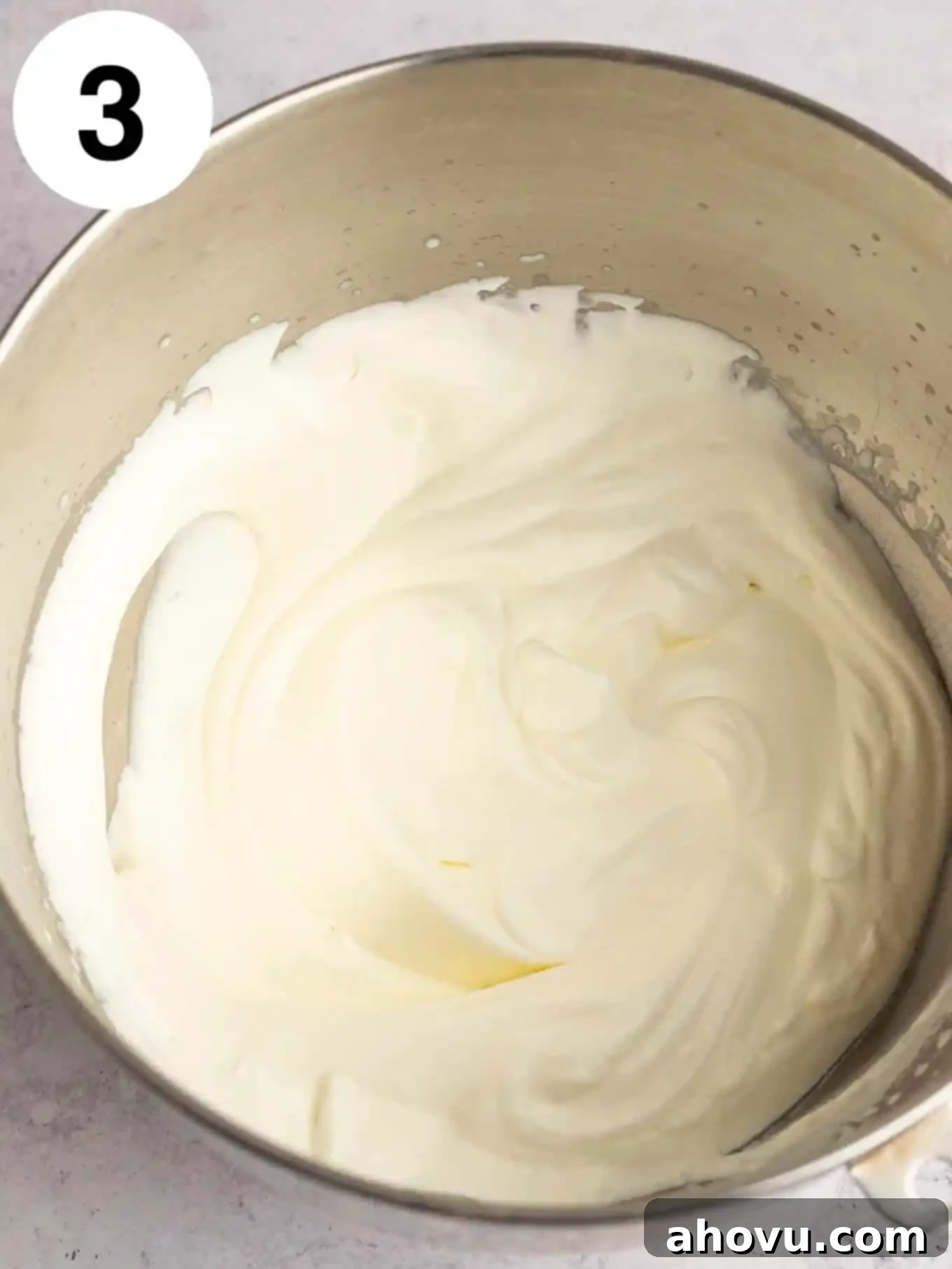 Whipped heavy cream in the bowl of a stand mixer, demonstrating stiff peaks.