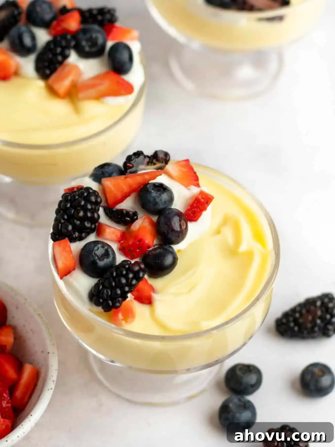 Creamy Vanilla Dream 2 An overhead view of two small dishes full of homemade vanilla pudding, topped with fresh berries and fluffy whipped cream, highlighting its inviting and delicious appearance, ready to be enjoyed as a classic dessert.