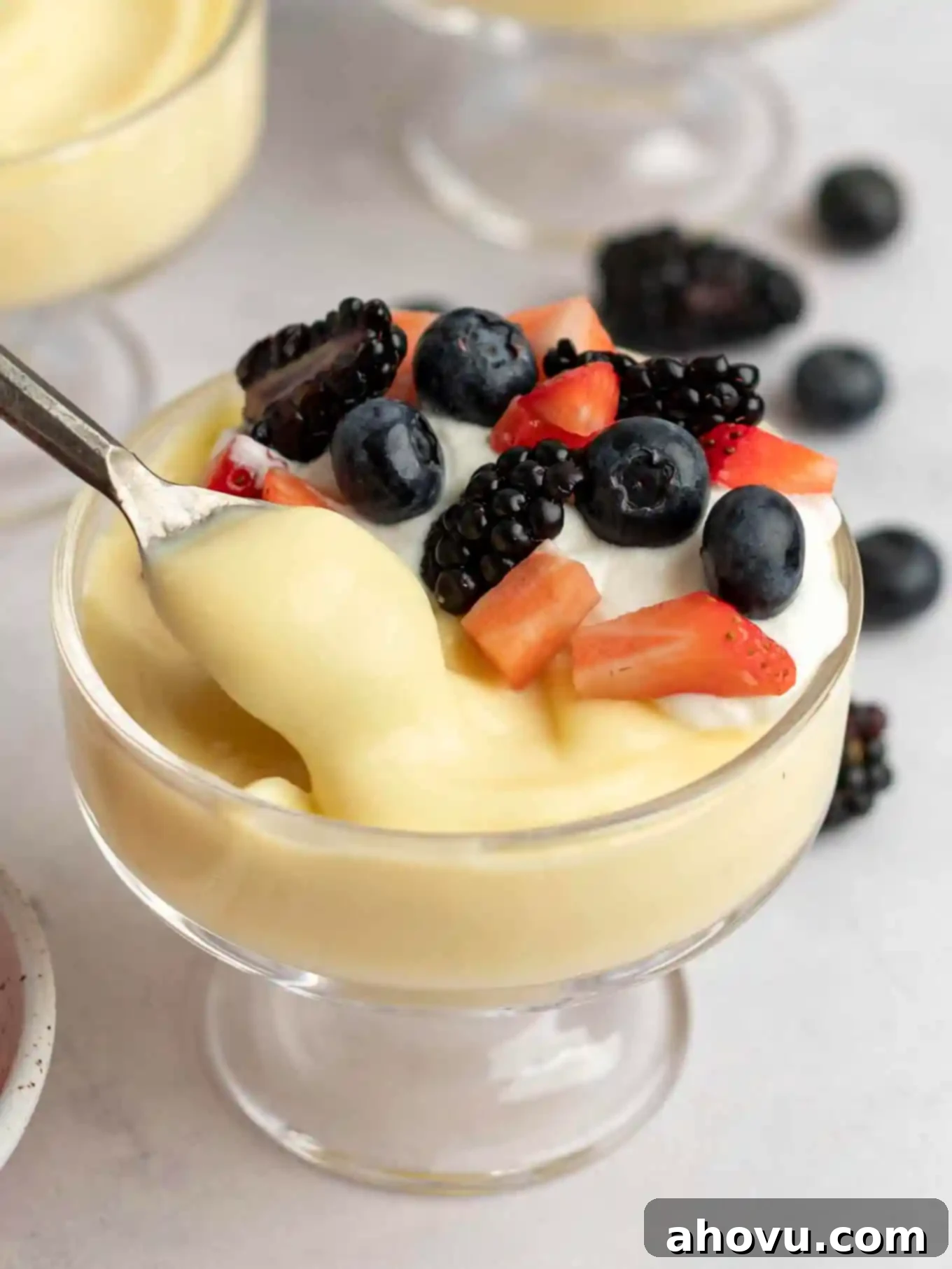 Creamy Vanilla Dream 11 A serving of vanilla pudding being spooned from a larger glass dish into a smaller dessert cup, showcasing its thick and creamy texture and ready for individual portions.