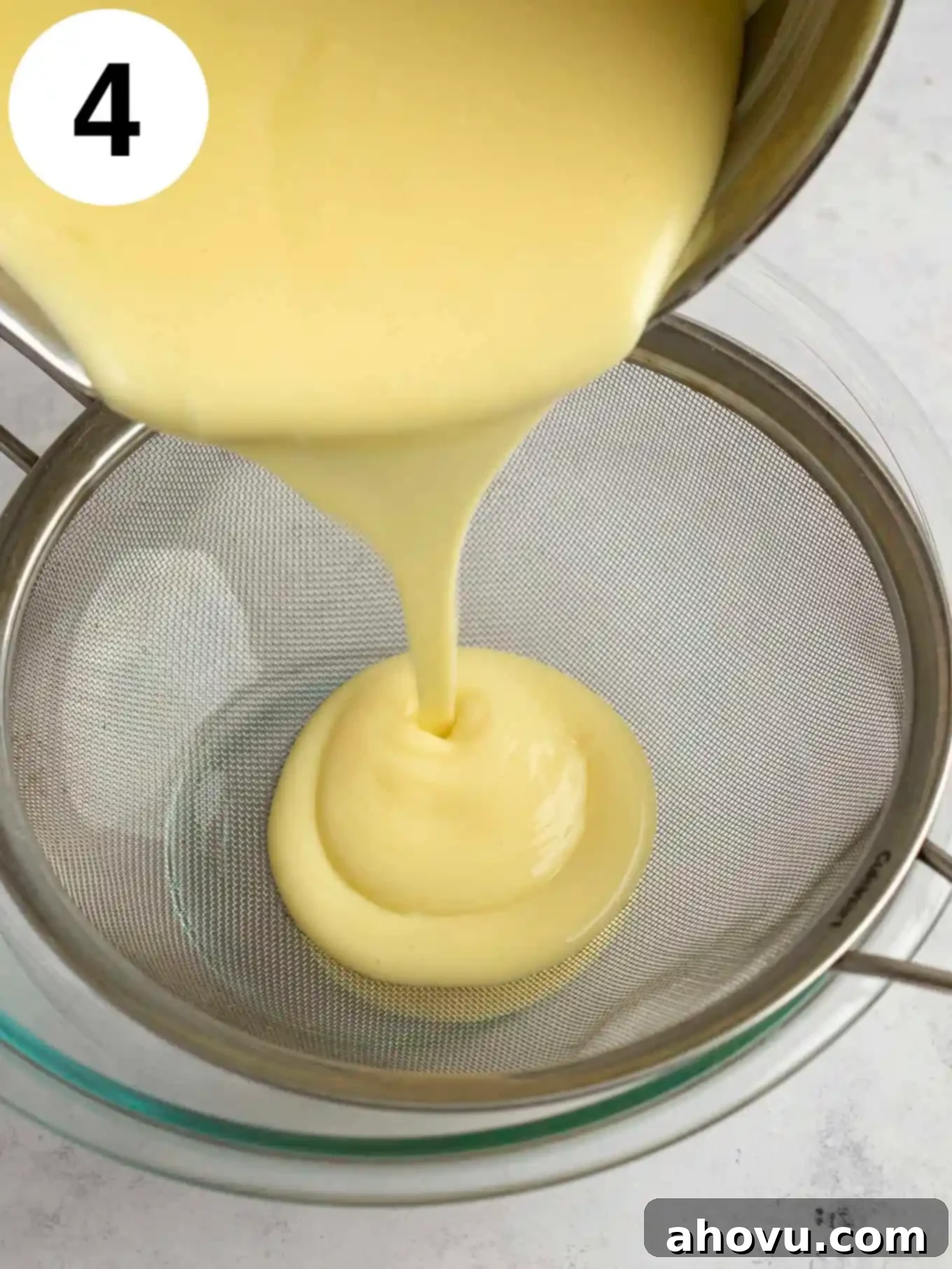 Creamy Vanilla Dream 7 A process shot showing the warm vanilla pudding being carefully strained through a fine-mesh sieve into a clean glass bowl, to remove any potential lumps and ensure a perfectly smooth texture for this homemade dessert.