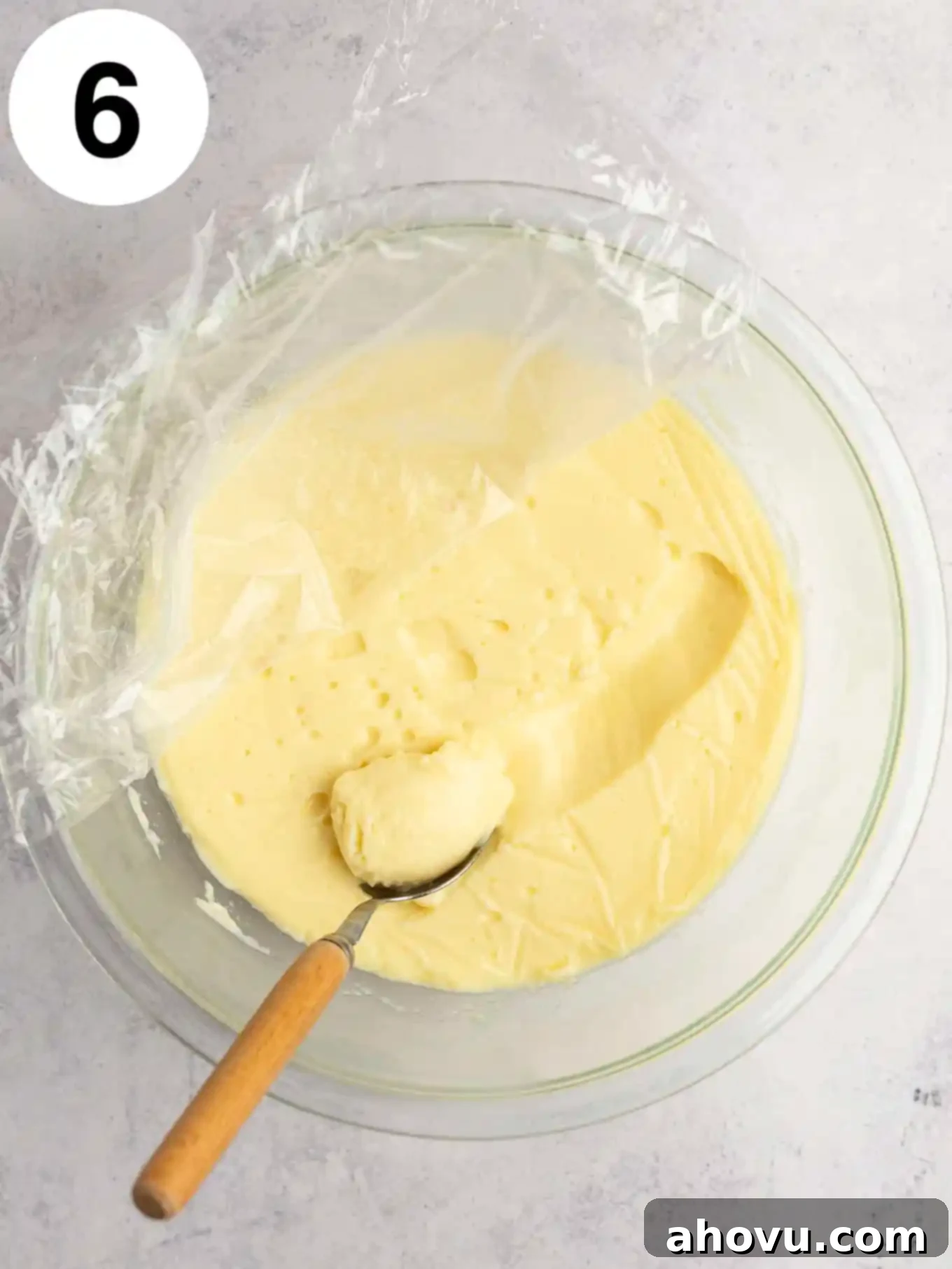 Creamy Vanilla Dream 9 A glass bowl with the plastic wrap peeled back to reveal the smooth, set vanilla pudding underneath, ready for chilling and showcasing its perfect texture.