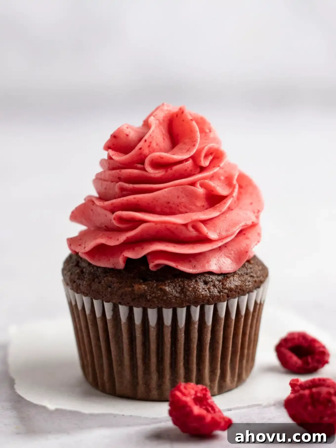 A chocolate cupcake topped with raspberry frosting. 