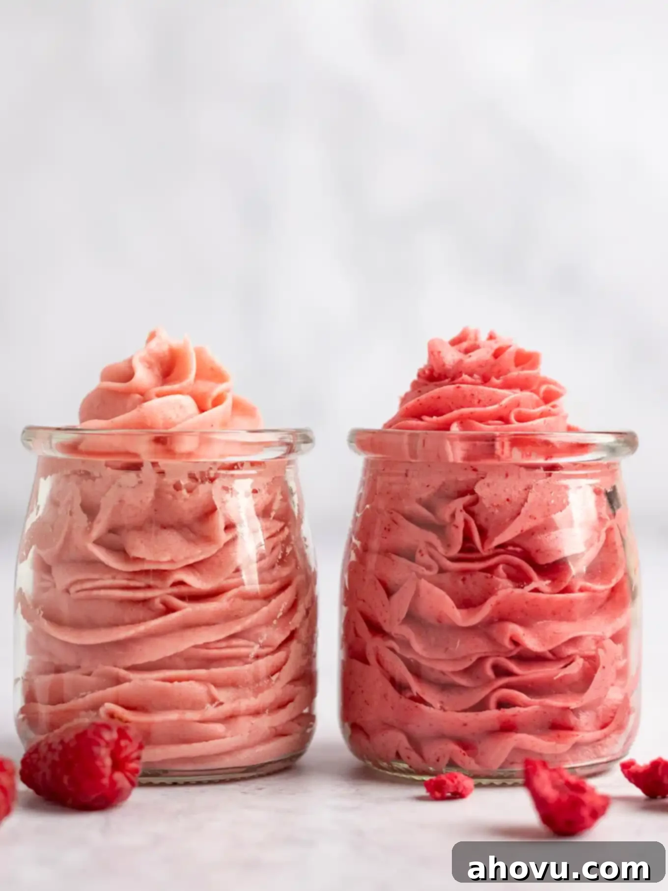 Two glass jars filled with raspberry frosting.