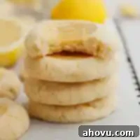 A stack of four perfectly baked lemon curd cookies, showcasing their golden shortbread and bright yellow filling.