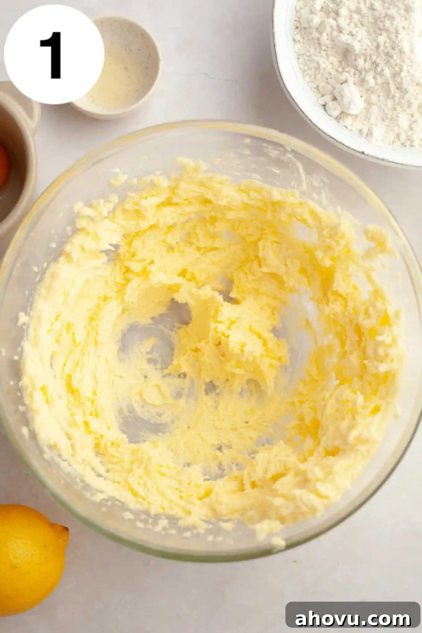 An overhead view of softened unsalted butter in a clear glass mixing bowl, ready for creaming.