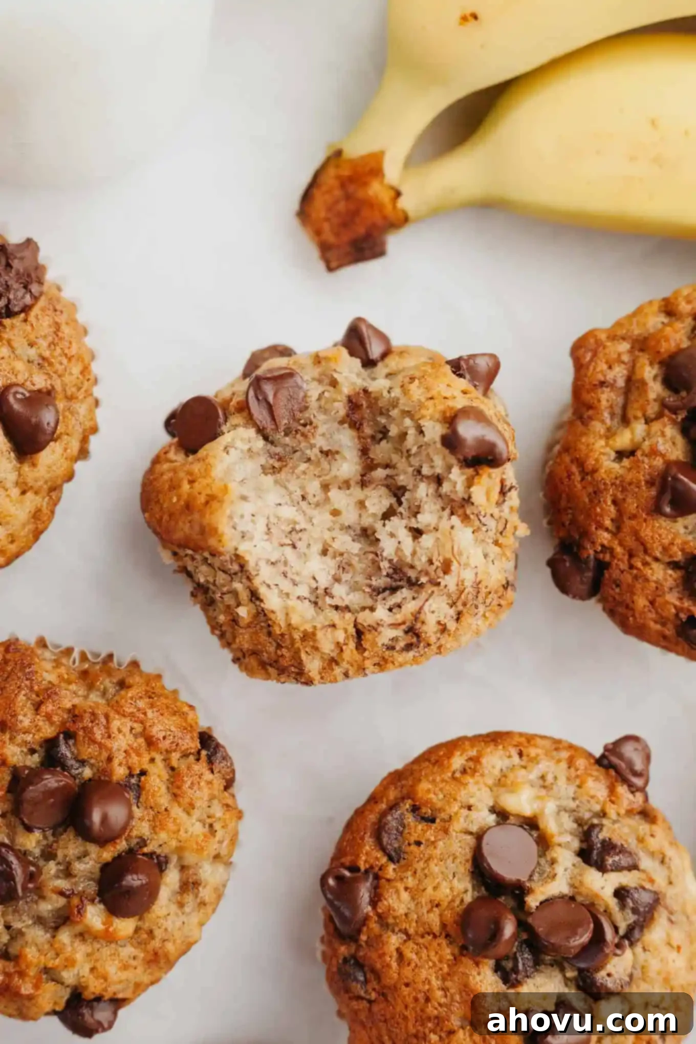 An overhead view of a banana chocolate chip muffin turned on its side, revealing its moist interior and generous chocolate chips, with a bite taken out.