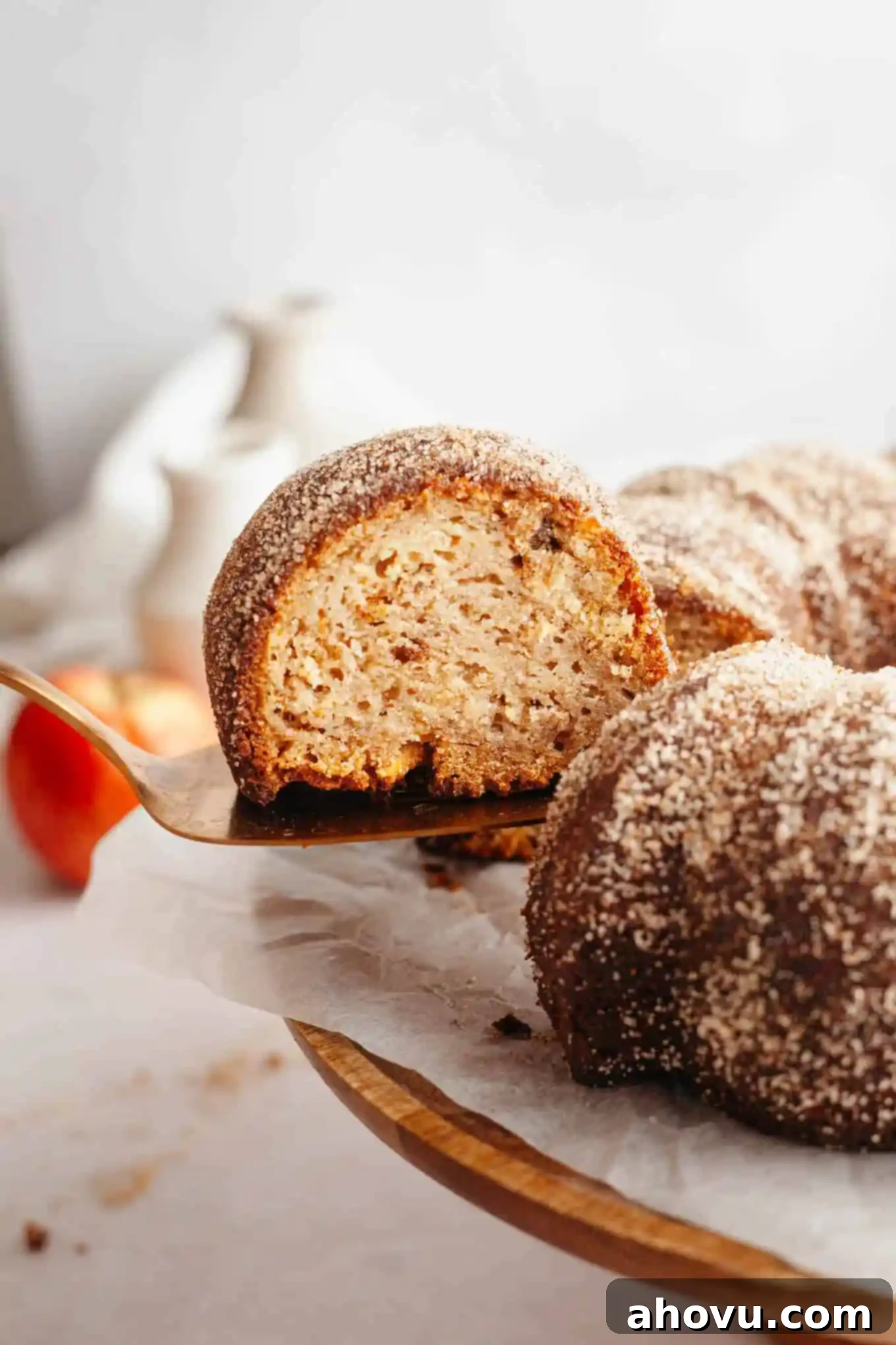 A luscious slice of apple cider donut cake being gracefully lifted from a cake stand, showcasing its inviting interior.