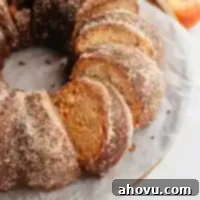An overhead view of a beautifully sliced apple cider donut cake, showcasing its moist texture and cinnamon sugar crust.