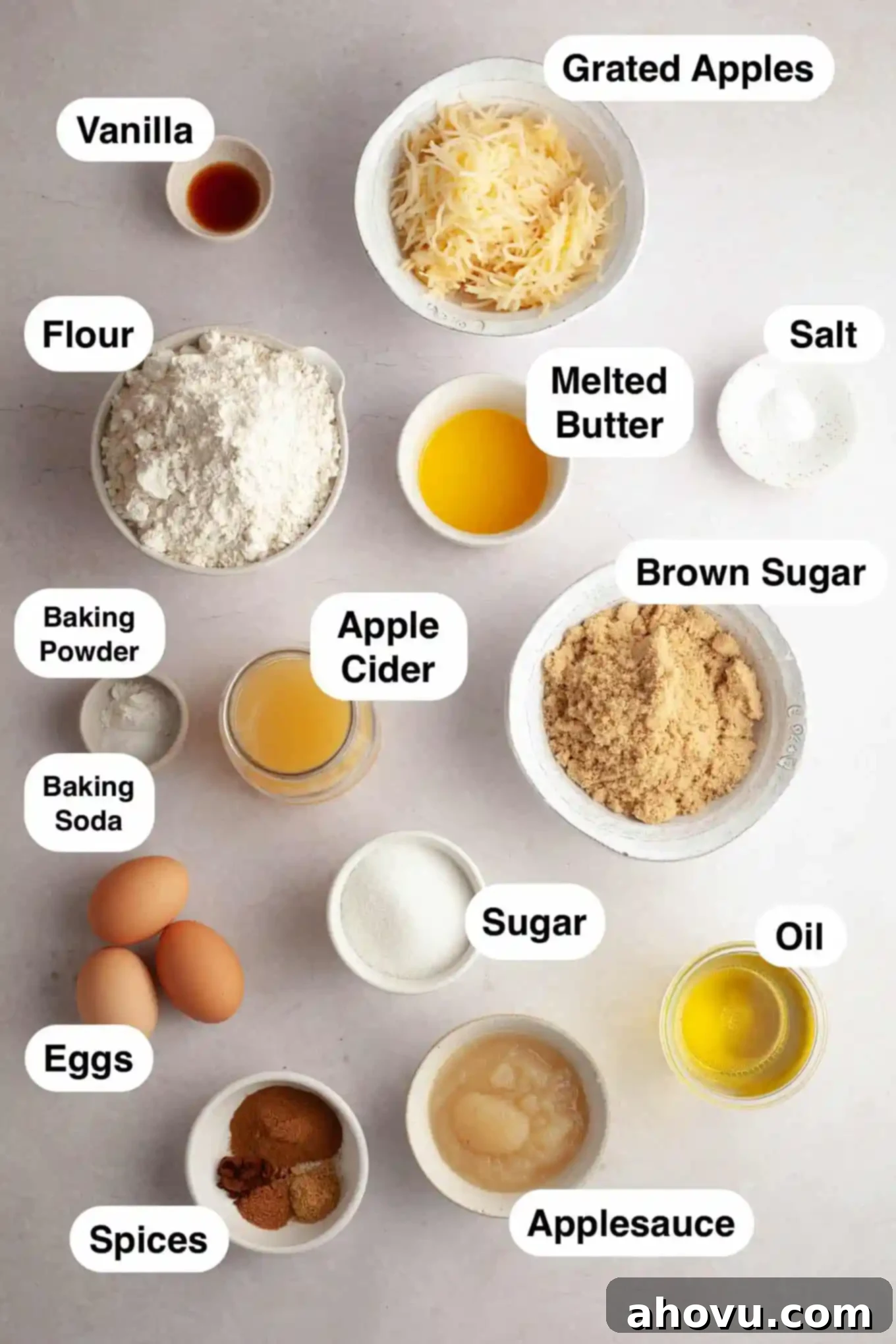 An overhead view of the ingredients needed to make an apple cider donut cake, including apples, applesauce, spices, and flour.