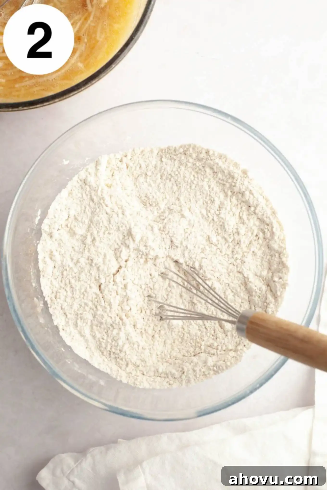 An overhead view of a flour and spice mixture, expertly whisked in a separate glass mixing bowl.