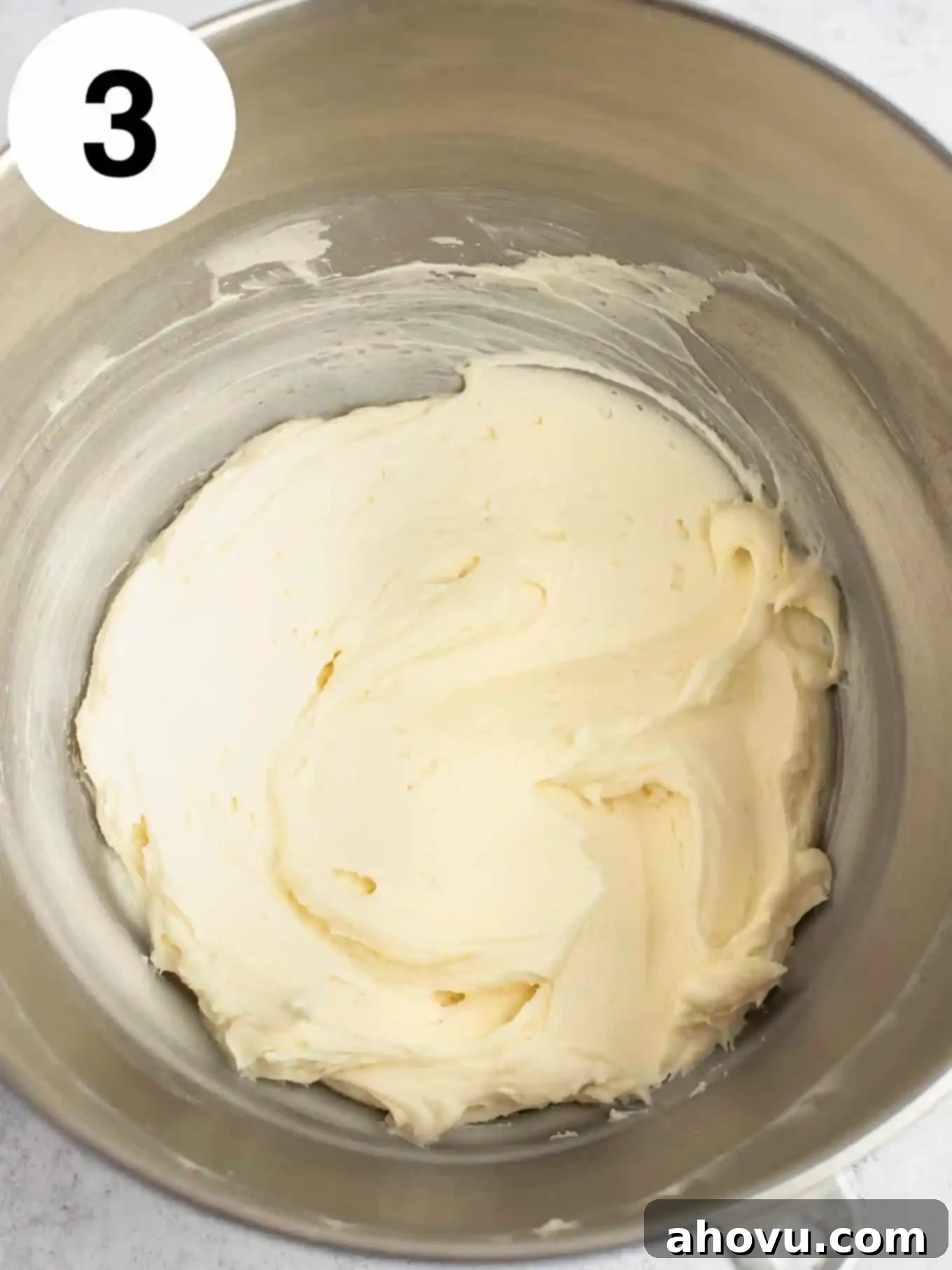 An overhead view of buttercream in a metal mixing bowl. 