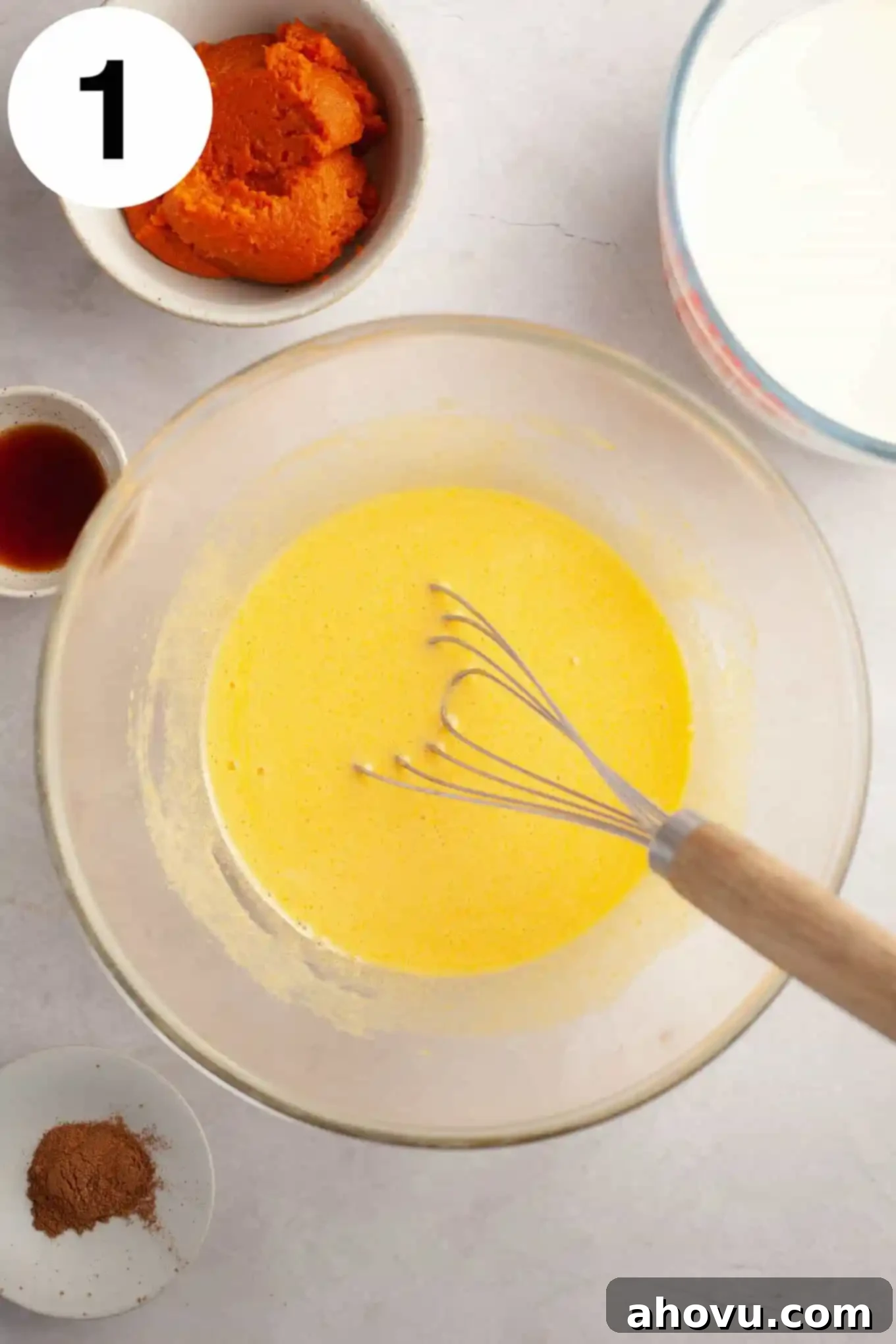 An overhead view of an egg yolks and granulated sugar mixture being whisked to a pale yellow color.
