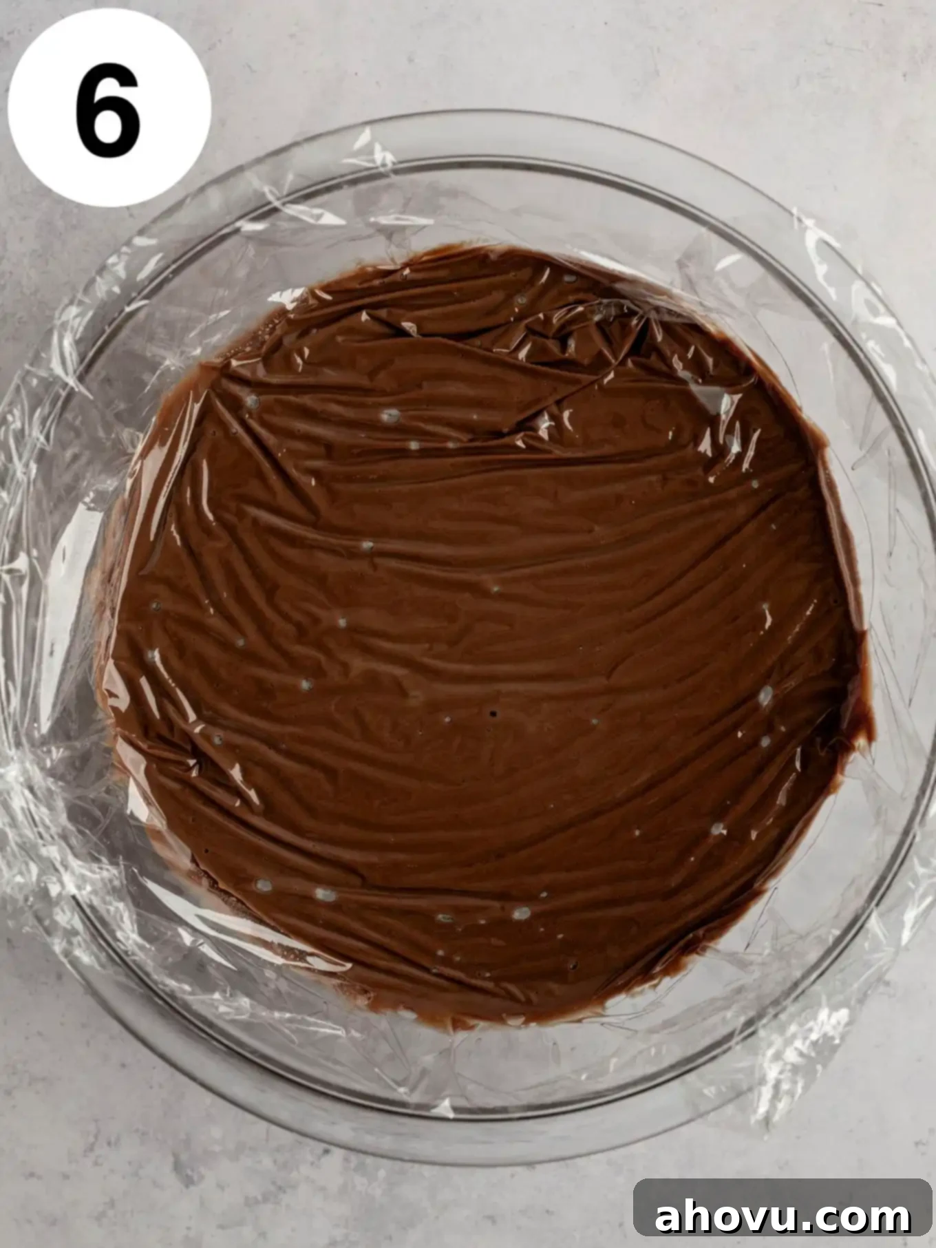 Decadent Chocolate Delight 9 An overhead view of chocolate pudding with plastic wrap pressed directly onto the surface.