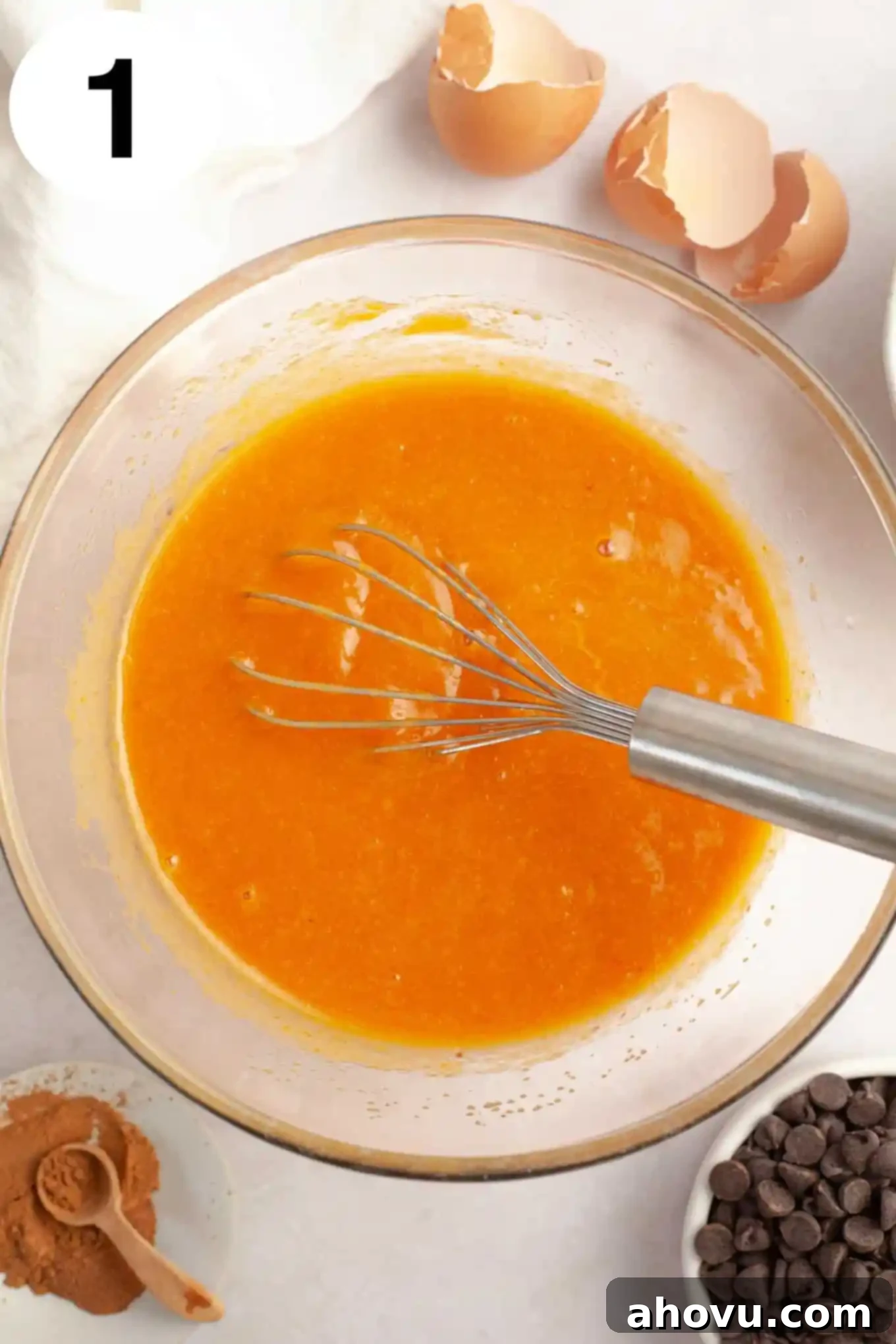 Cozy Pumpkin Chocolate Morsel Muffins 4 An overhead view of a wet pumpkin mixture in a mixing bowl, with a whisk.