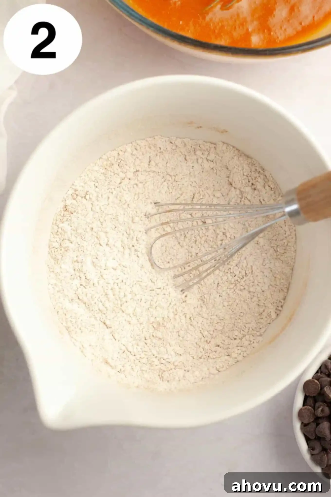 Cozy Pumpkin Chocolate Morsel Muffins 5 An overhead view of a dry flour mixture in a mixing bowl, with a whisk.