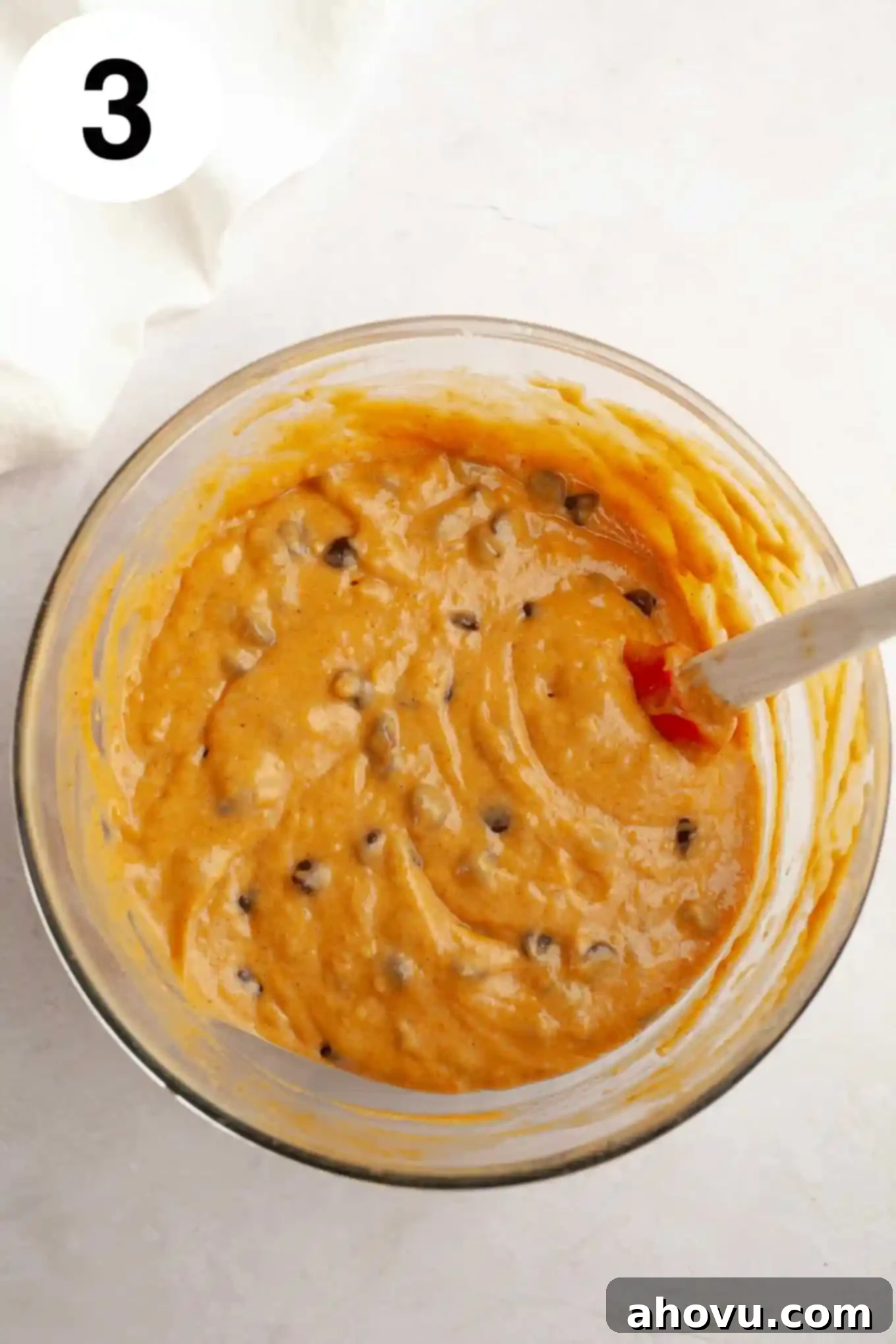 Cozy Pumpkin Chocolate Morsel Muffins 6 An overhead view of pumpkin chocolate chip muffin batter in a mixing bowl, with a rubber spatula.