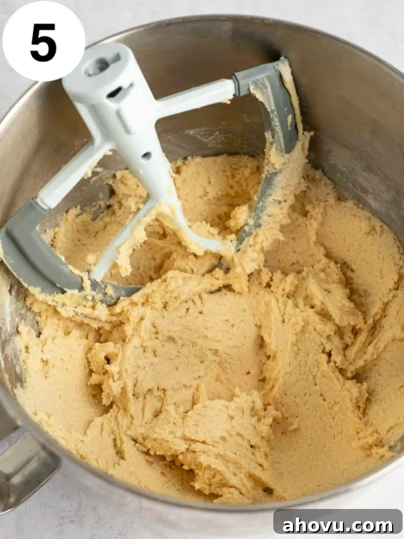 An overhead view of the completed cookie dough frosting in the stand mixer bowl, showcasing its rich texture and readiness for chocolate chips.