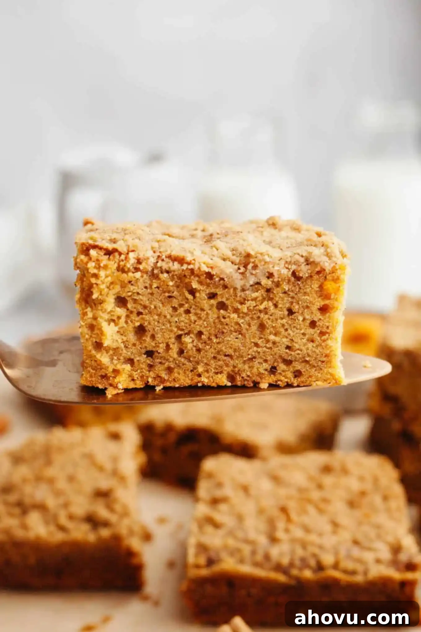 A slice of pumpkin coffee cake being held aloft on a spatula. 