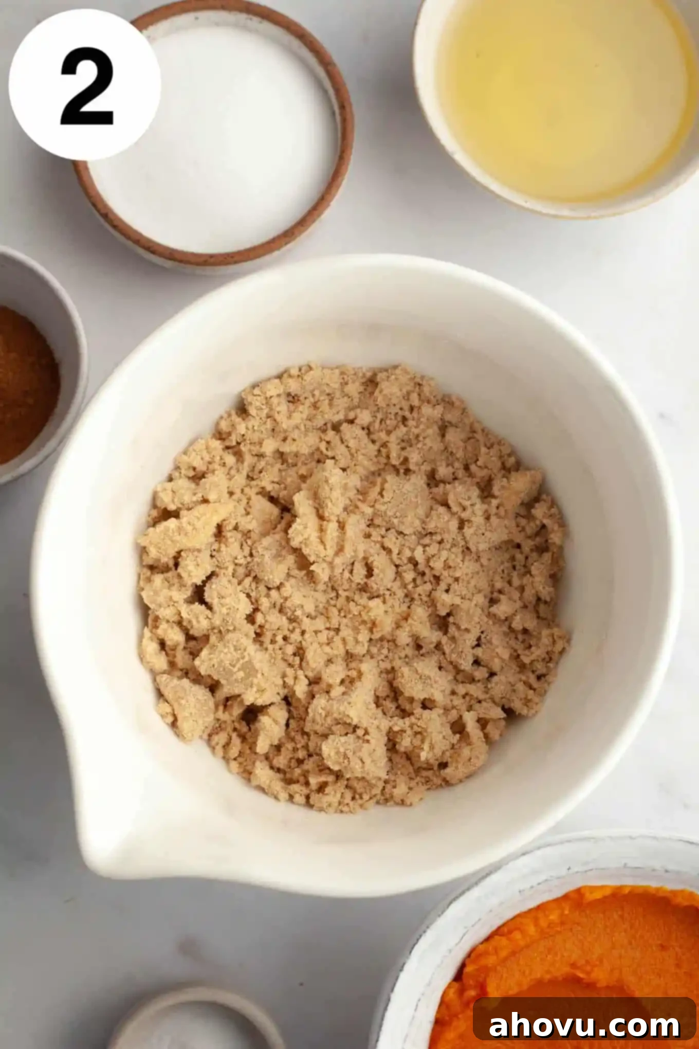 An overhead view of a cinnamon streusel mixture in a white mixing bowl.
