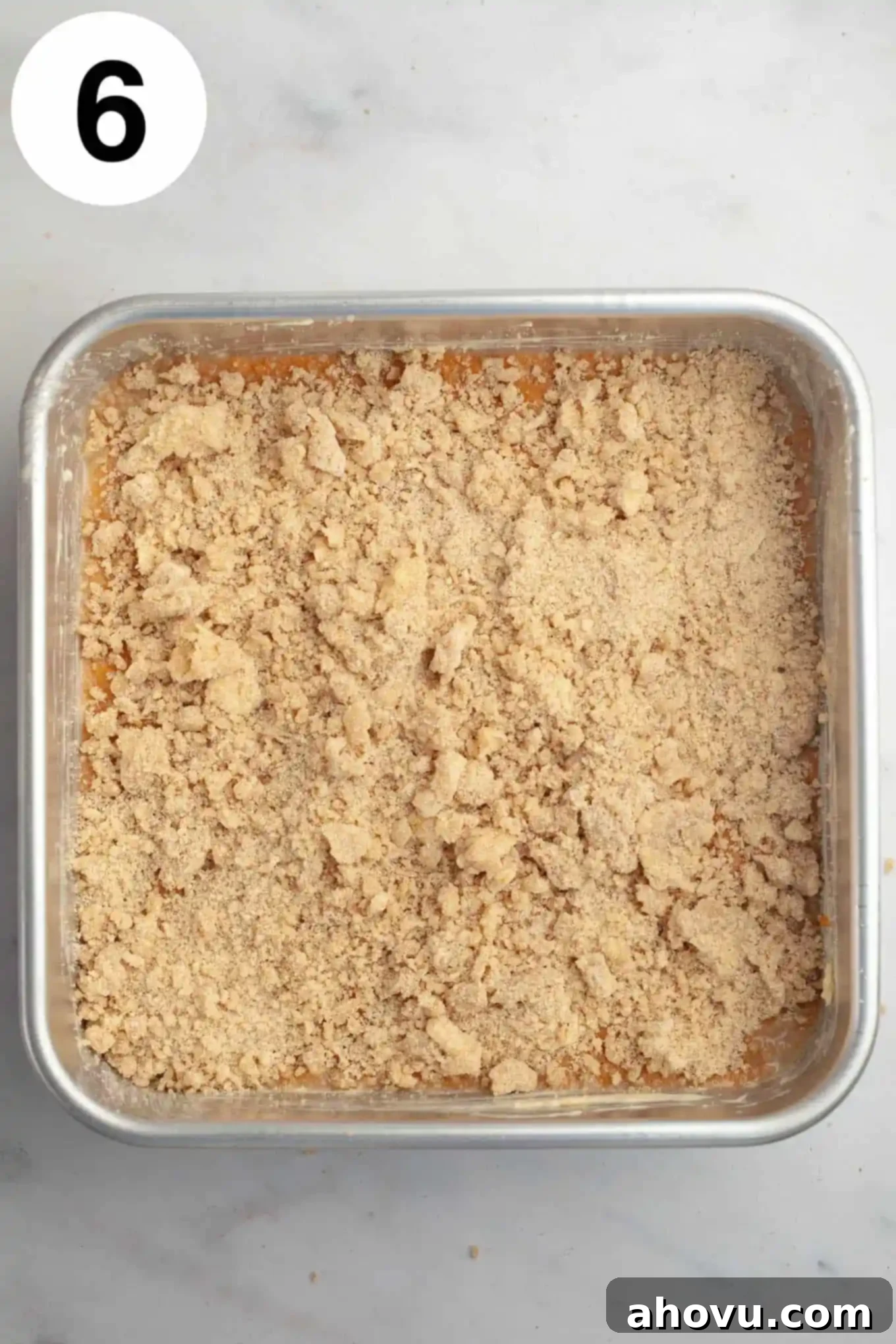 An overhead view of an unbaked pumpkin streusel coffee cake. 