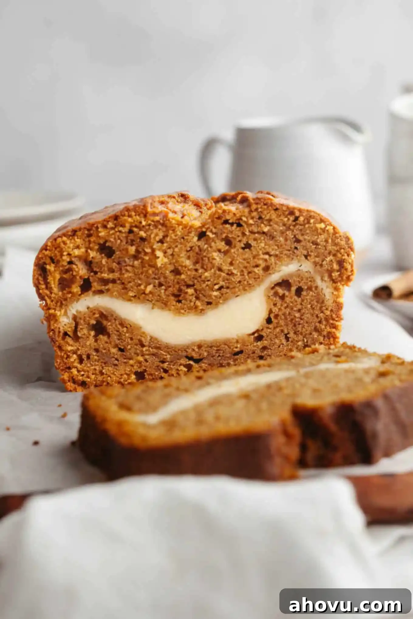 Pumpkin Swirl Cream Cheese Bread 2 A side view of a perfectly sliced loaf of pumpkin bread revealing a thick, creamy layer of cream cheese filling in the center.