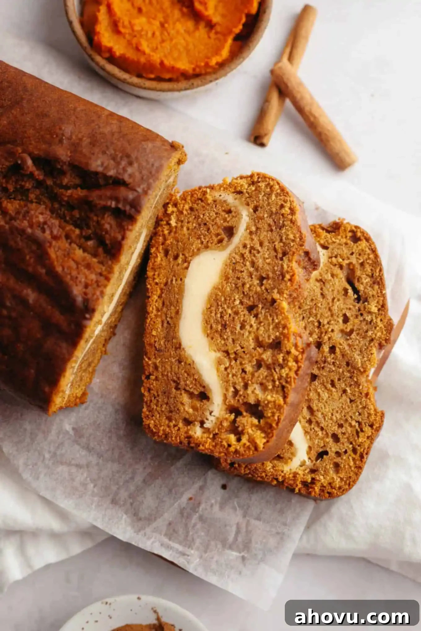 Pumpkin Swirl Cream Cheese Bread 11 A close-up, overhead shot of two elegant slices of pumpkin cream cheese bread, arranged on their sides to highlight the distinct layers of spiced pumpkin bread and the rich cream cheese swirl.