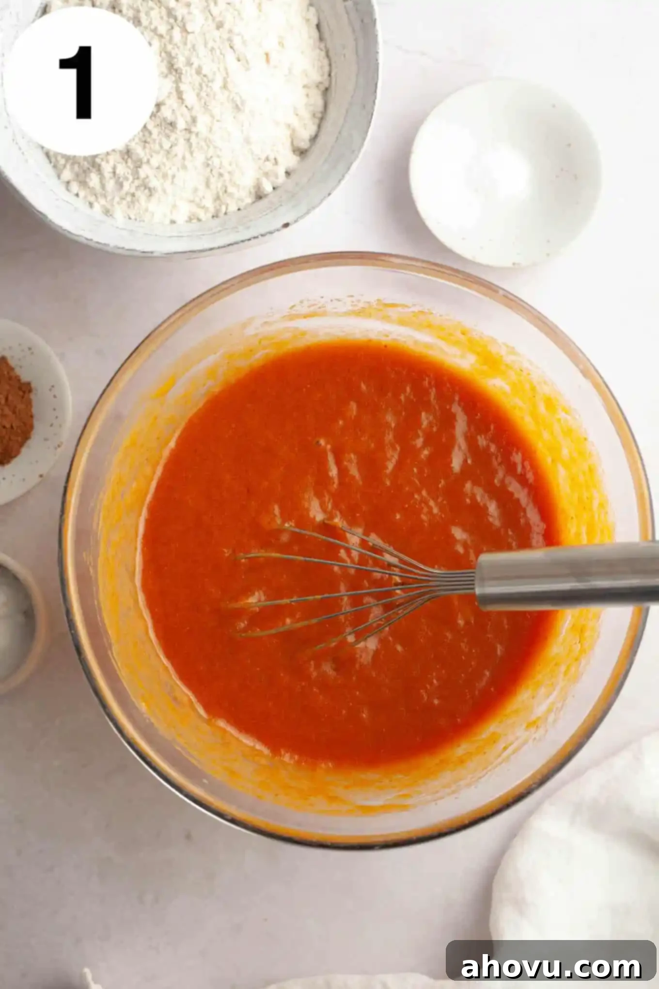 Pumpkin Swirl Cream Cheese Bread 4 An overhead view of a rich, orange pumpkin puree mixture being whisked in a clear glass bowl, showcasing its smooth texture.
