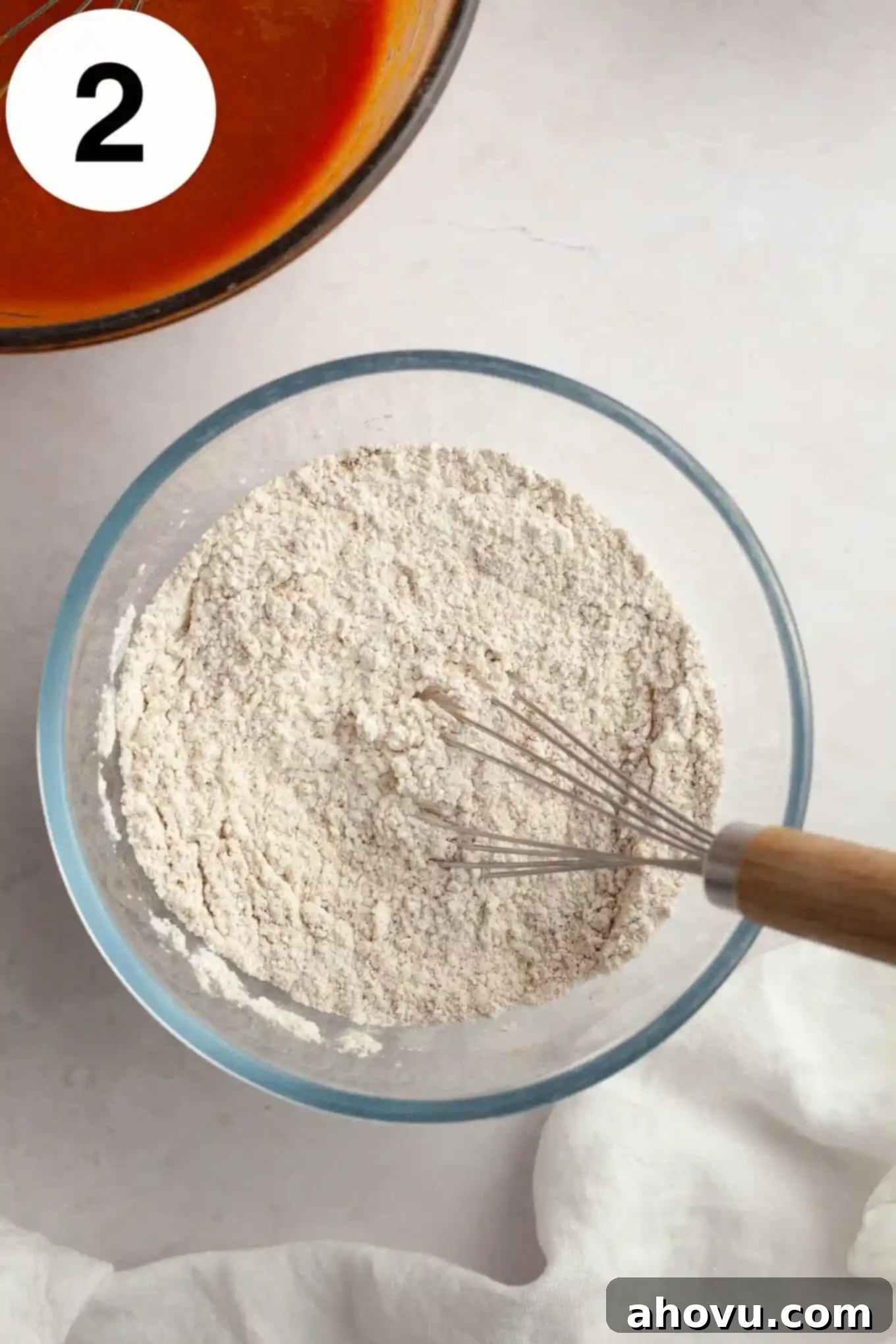 Pumpkin Swirl Cream Cheese Bread 5 An overhead view of a bowl filled with dry ingredients like flour and spices, being whisked together to create a uniform mixture.