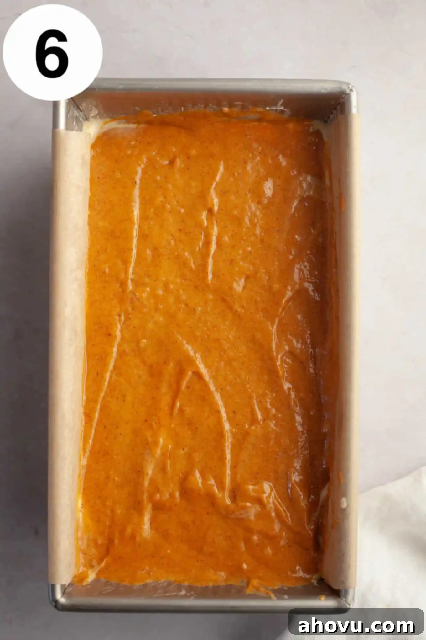 Pumpkin Swirl Cream Cheese Bread 9 An overhead view of an unbaked loaf of pumpkin bread in a loaf pan, showing the top layer of pumpkin batter covering the cream cheese filling, ready for the oven.