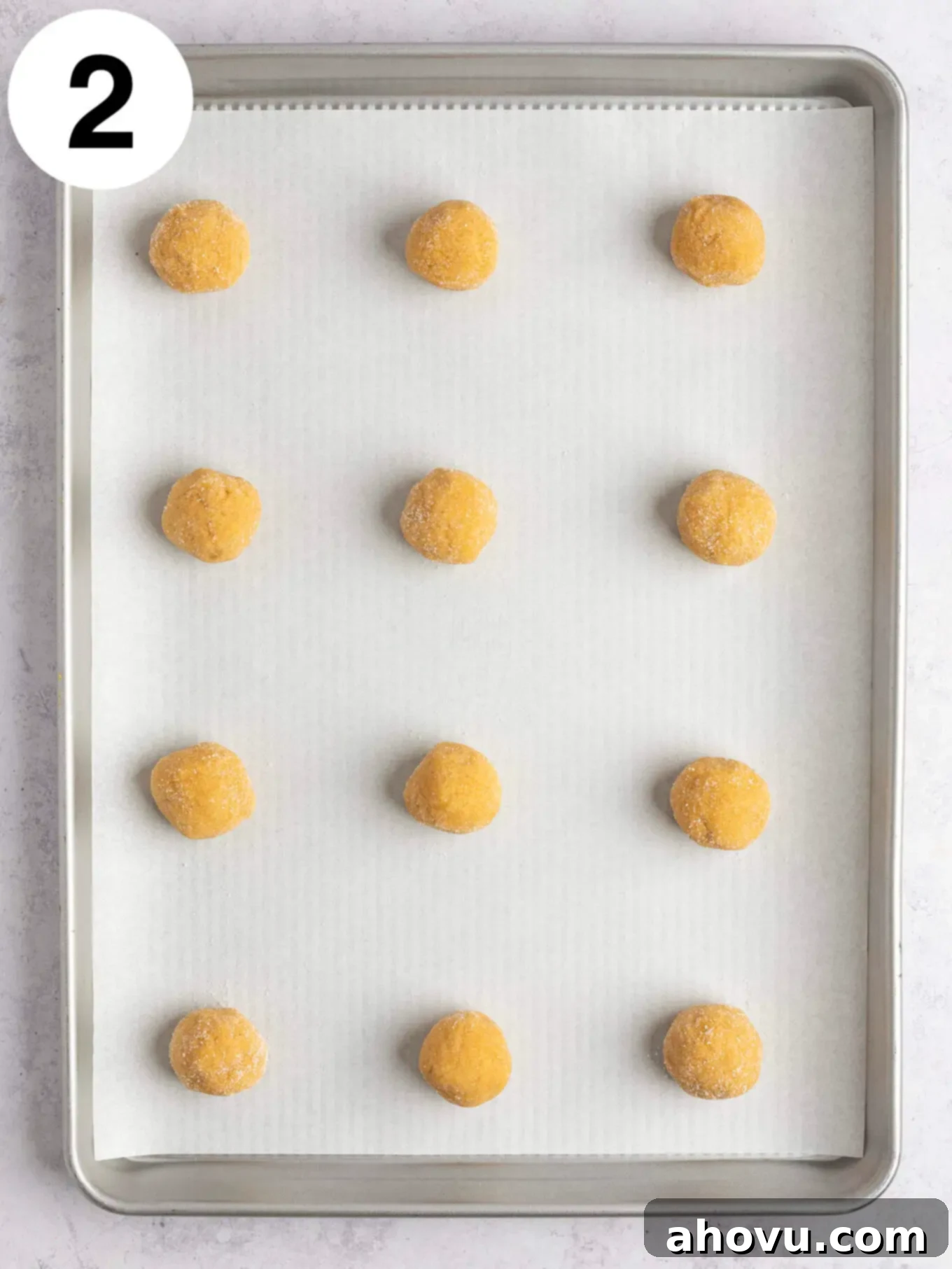 Creepy Crawly Cookie Bites 5 An overhead view of peanut butter cookie dough balls on a parchment paper-lined baking sheet.