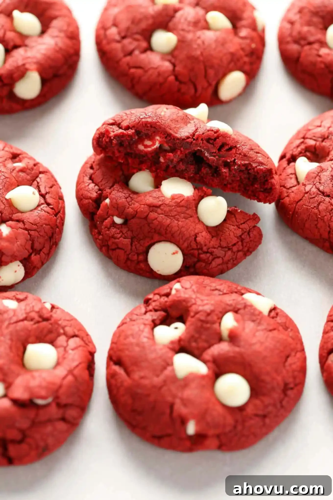 Effortless Red Velvet Delights 3 A close-up of three red velvet cake mix cookies, one broken in half to show the soft, moist interior and white chocolate chips.