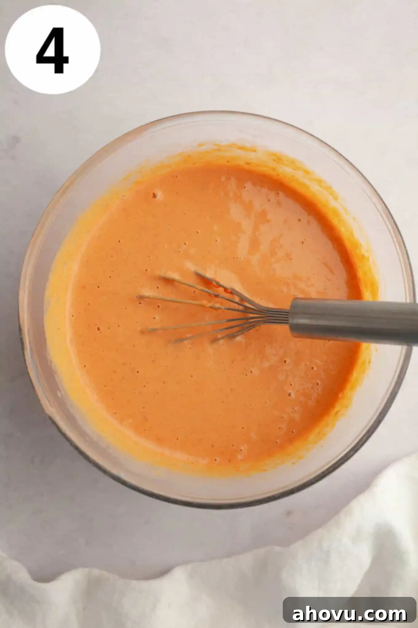 Harvest Spice Pumpkin Bars 7 An overhead view of a pumpkin puree and egg mixture in a mixing bowl, with a whisk.