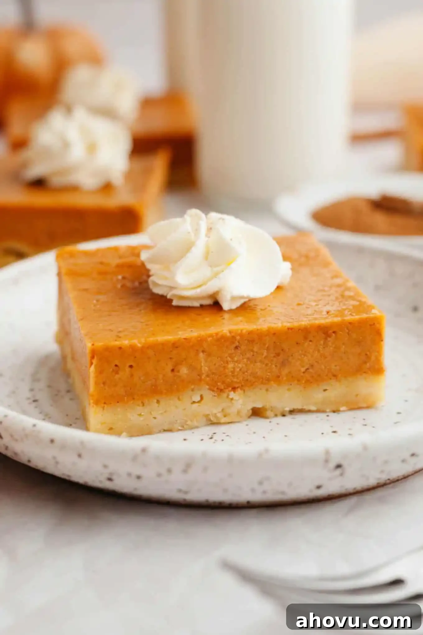 Harvest Spice Pumpkin Bars 10 A pumpkin pie bar garnished with whipped cream, on a dessert plate.
