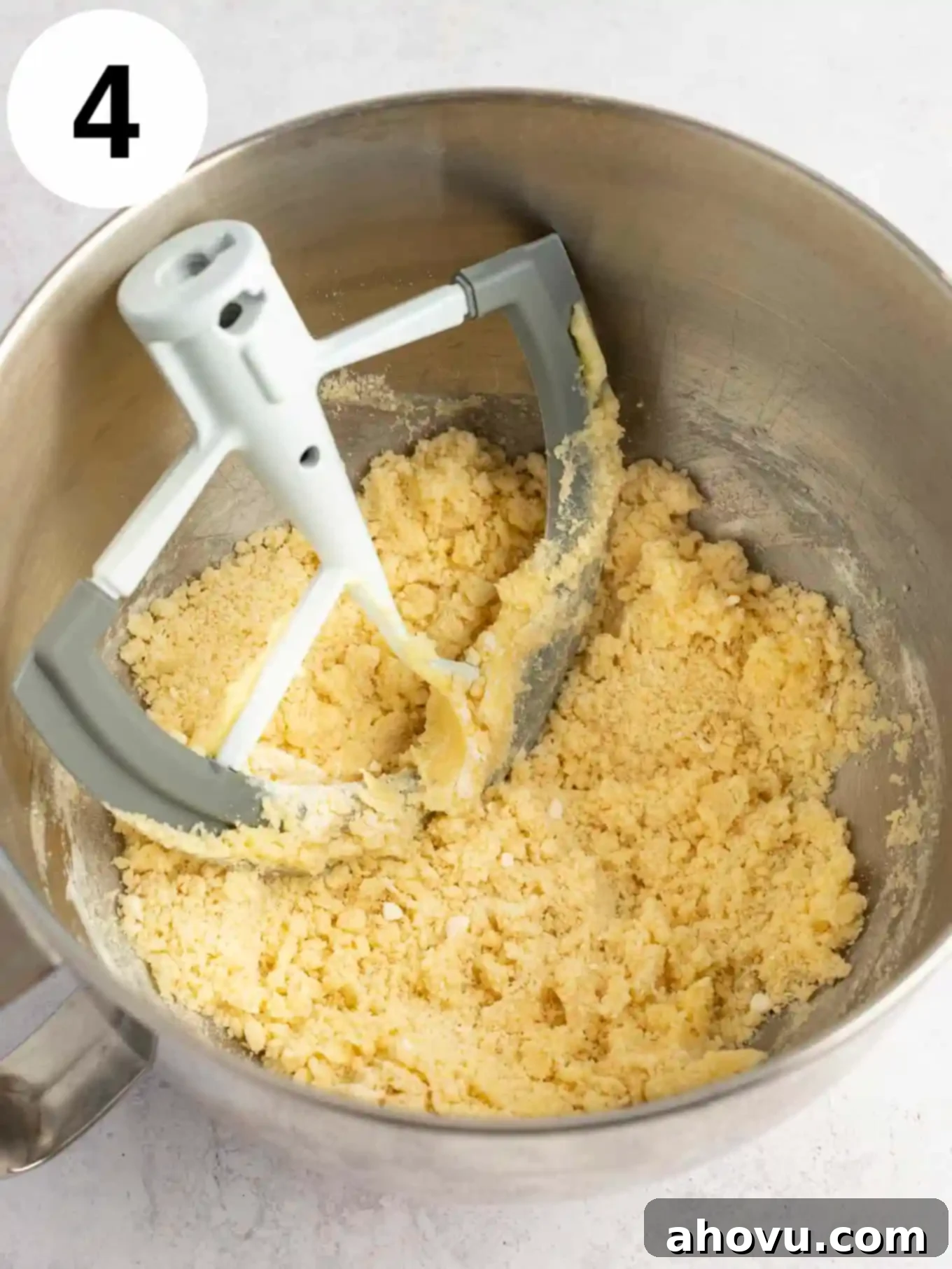 Guilt-Free Sugar Cookie Dough 7 An overhead view of the heat-treated flour being sifted into the creamed butter and sugar mixture in a mixing bowl.