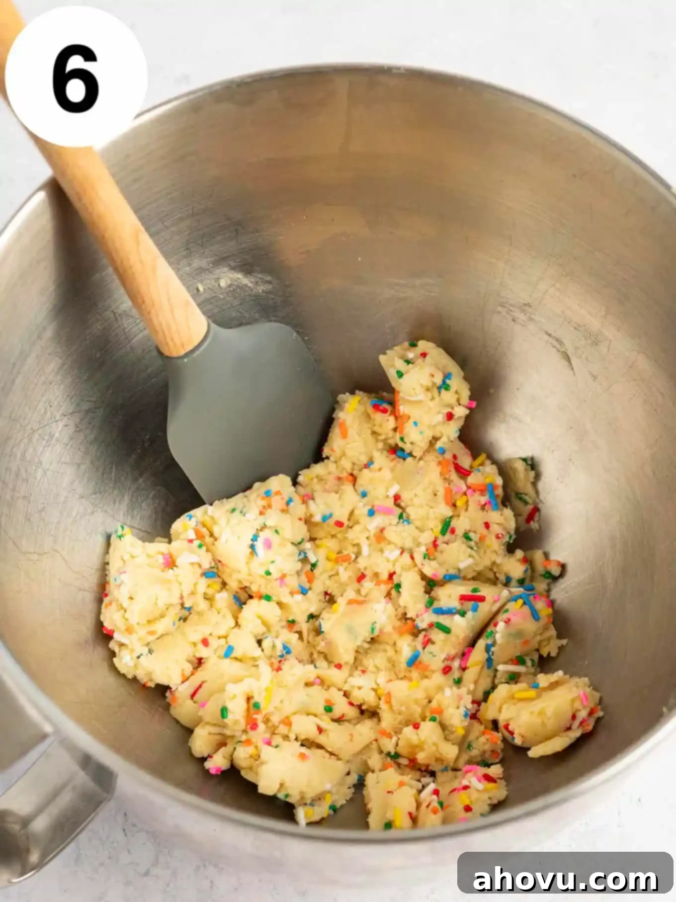 Guilt-Free Sugar Cookie Dough 9 An overhead view of the finished sugar cookie dough, flecked with colorful sprinkles, in a mixing bowl with a rubber spatula.