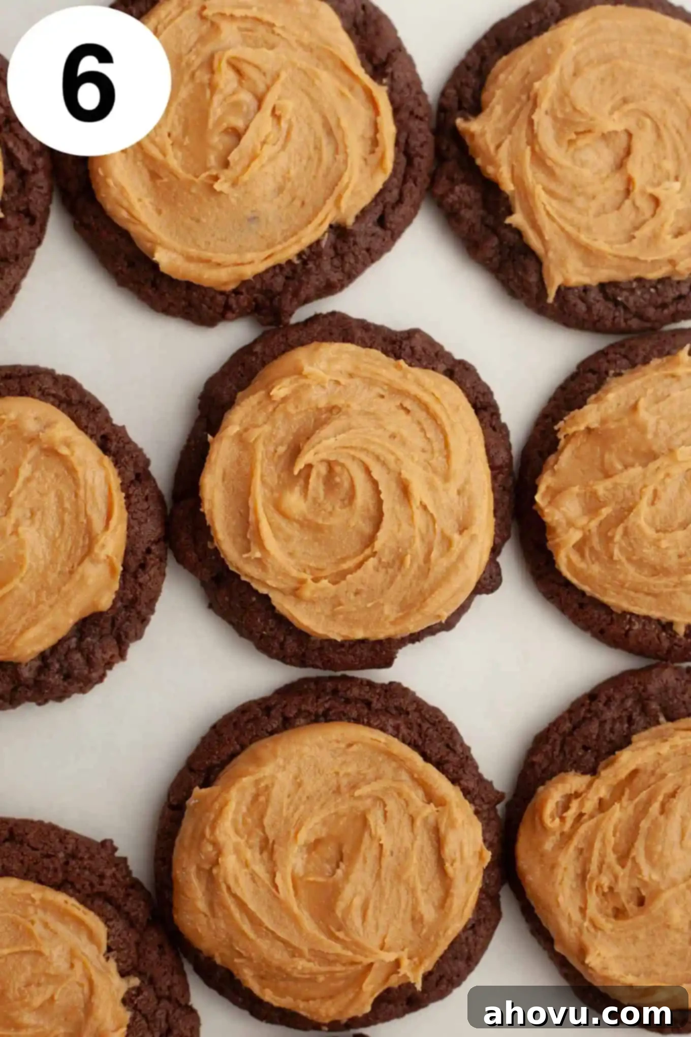 An overhead view of perfectly cooled chocolate cookies, each generously topped with a dollop of creamy peanut butter mixture, mimicking the classic Buckeye candy shape.