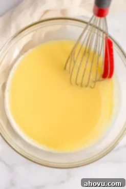 The lemon filling inside of a glass bowl with a whisk on the side.