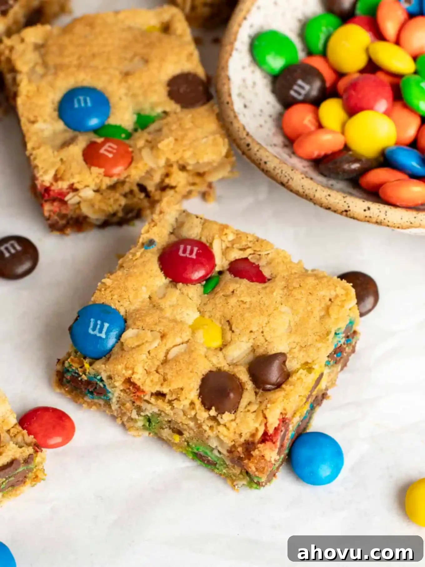 A close up view of a monster bar cookie next to a dish of M&M's.