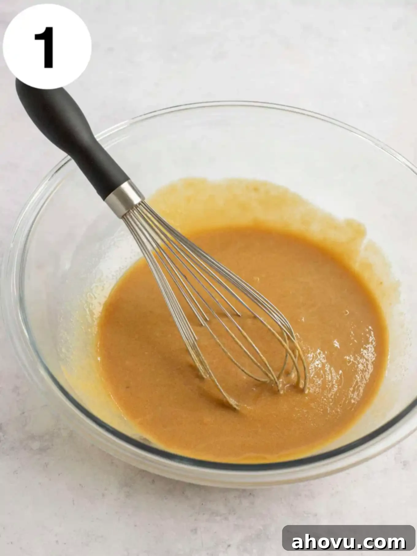 Melted butter and peanut butter in a glass mixing bowl with a whisk. 