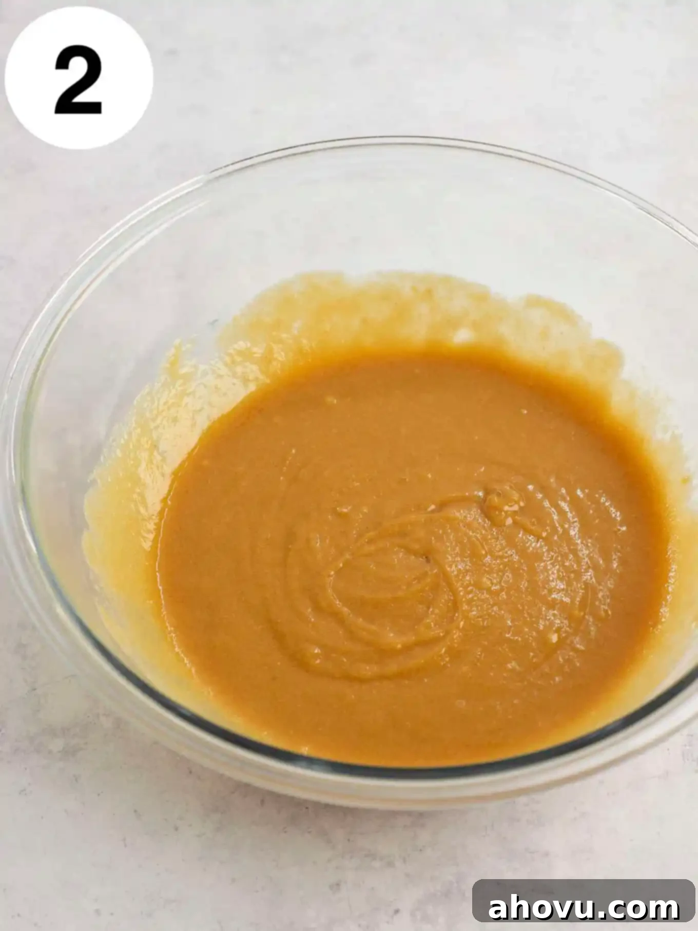 Melted butter, peanut butter, eggs, and brown sugar in a glass mixing bowl with a whisk. 