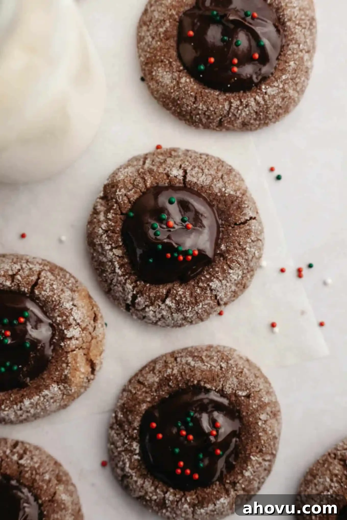 Irresistible Chocolate Thumbprint Cookies 11 An overhead view of chocolate thumbprint cookies topped with red and green nonpareils.