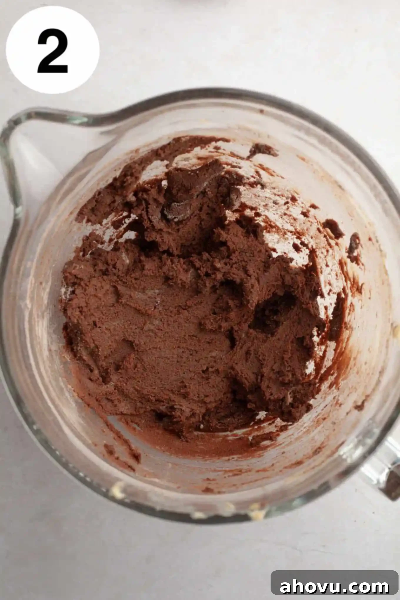 Irresistible Chocolate Thumbprint Cookies 5 An overhead view of chocolate cookie dough in a glass mixing bowl.