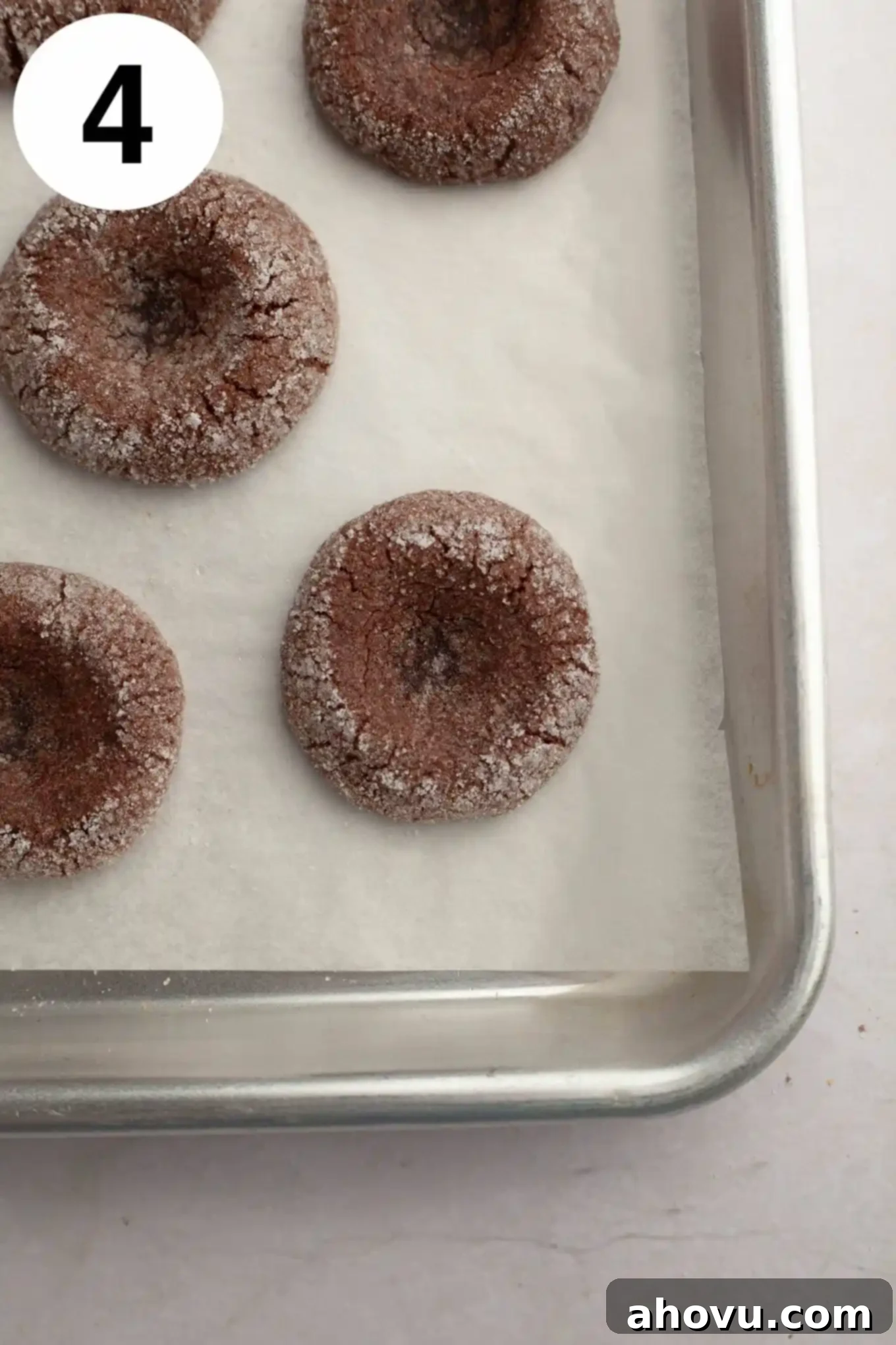 Irresistible Chocolate Thumbprint Cookies 7 Baked and unfilled chocolate thumbprint cookies on a parchment lined baking sheet.