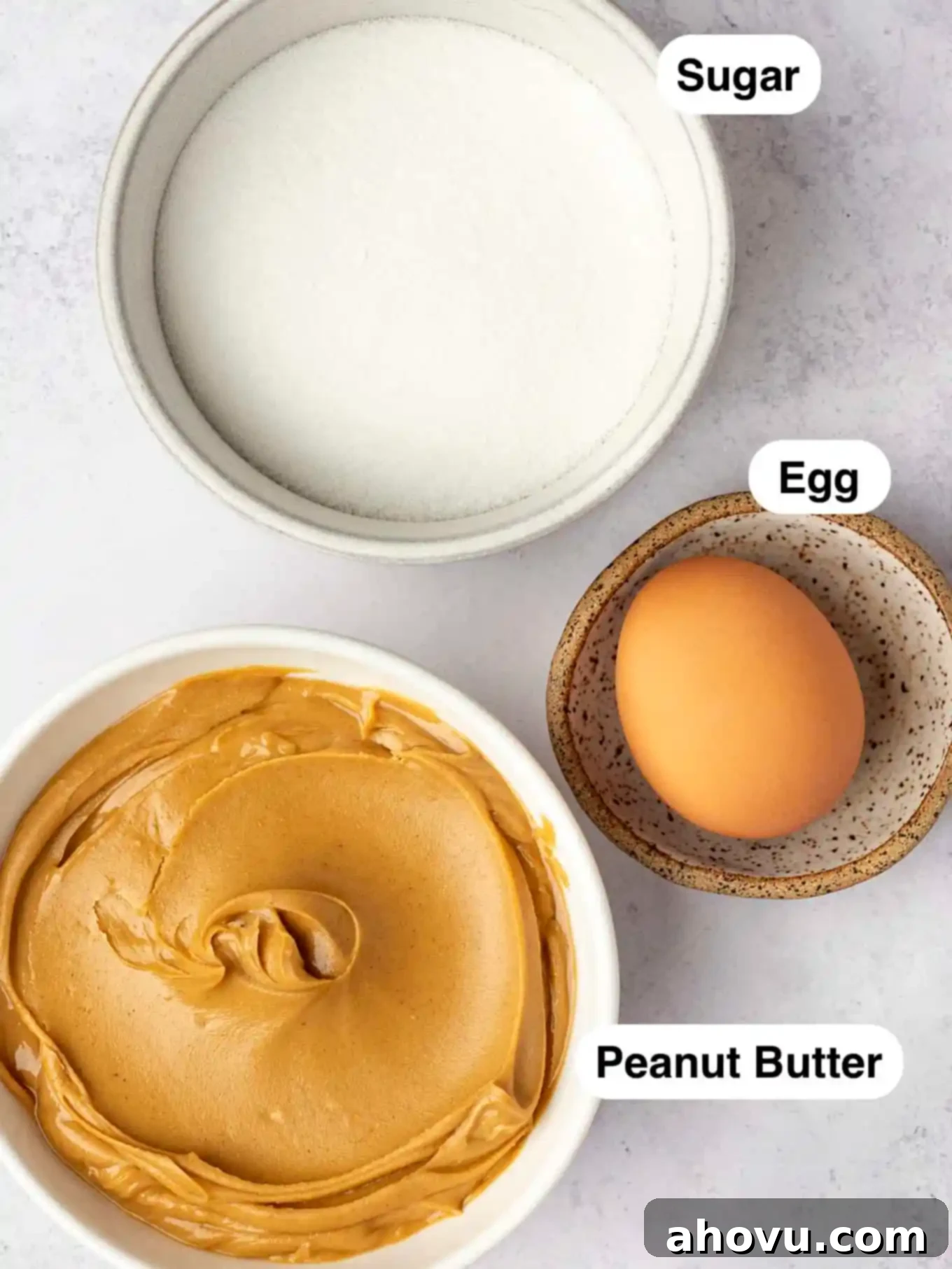 An overhead view of sugar, an egg, and peanut butter in individual dishes. 