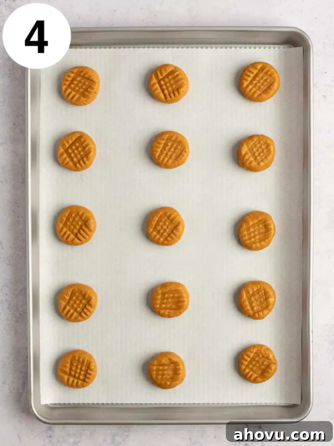 An overhead view of peanut butter cookie dough balls that have been pressed down with a fork. 